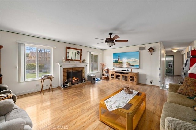 living room featuring hardwood / wood-style flooring, ceiling fan, and a fireplace