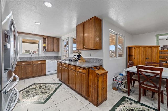 kitchen featuring white dishwasher, stainless steel fridge with ice dispenser, a healthy amount of sunlight, and light tile patterned flooring