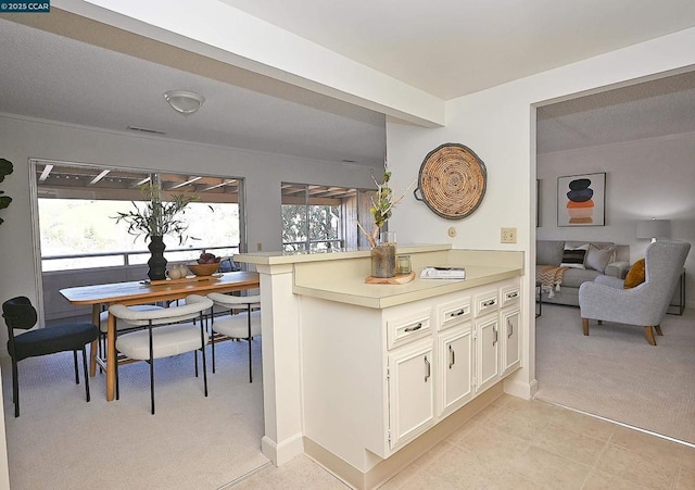 kitchen with white cabinetry, light carpet, and kitchen peninsula