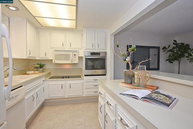 kitchen featuring white cabinetry, sink, light tile patterned floors, and white appliances