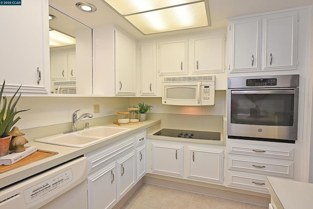 kitchen featuring white appliances, light tile patterned floors, sink, and white cabinets