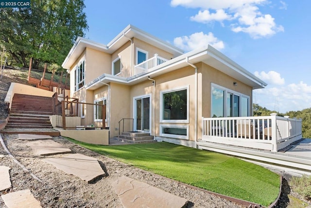 rear view of house featuring a balcony and a yard