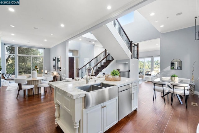 kitchen featuring dark hardwood / wood-style floors, white cabinetry, an island with sink, sink, and stainless steel dishwasher