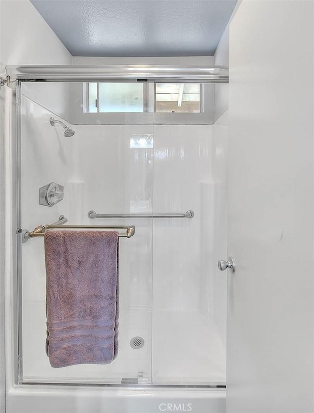 bathroom with a textured ceiling, a healthy amount of sunlight, and walk in shower