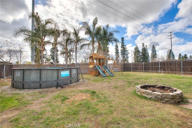 view of yard with a fenced in pool, a playground, and an outdoor fire pit