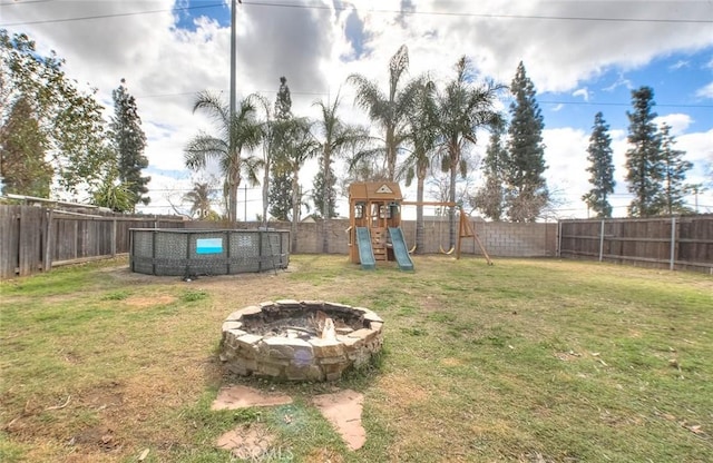 view of yard featuring a playground, a pool, and an outdoor fire pit