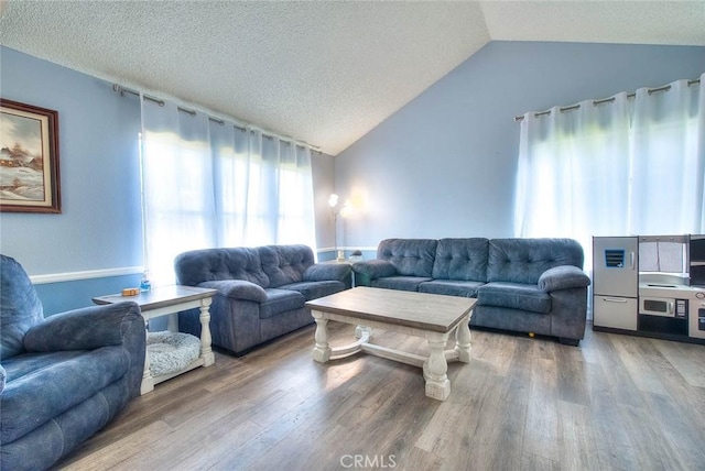 living room with hardwood / wood-style floors, vaulted ceiling, and a textured ceiling