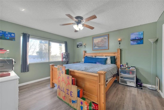 bedroom featuring ceiling fan, hardwood / wood-style flooring, and a textured ceiling