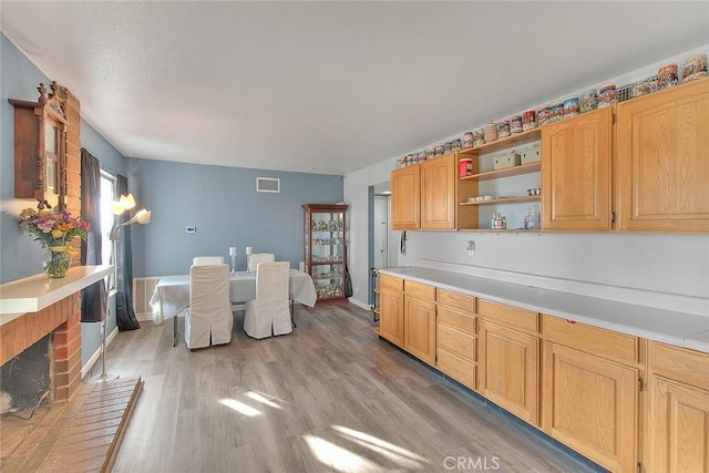 kitchen with a brick fireplace and light hardwood / wood-style floors