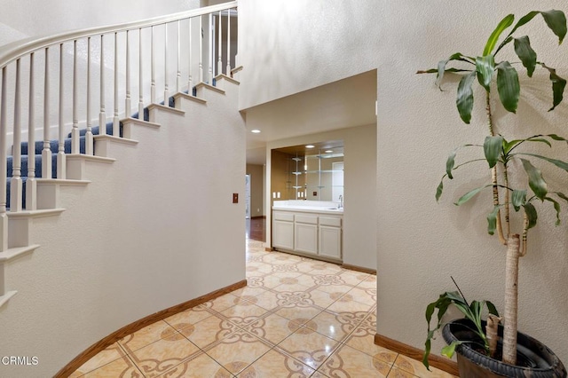 stairway with a high ceiling, sink, and tile patterned floors