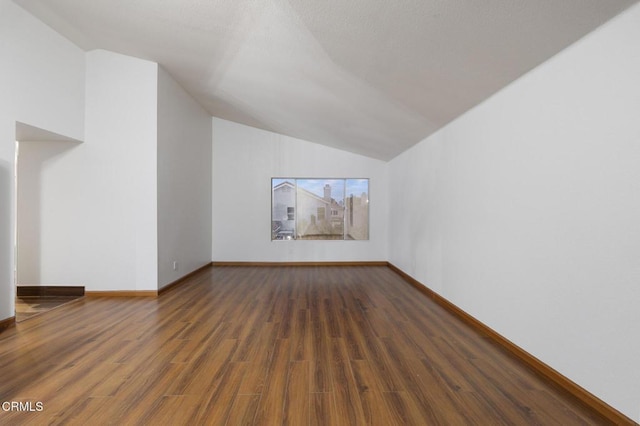 additional living space featuring dark wood-type flooring and vaulted ceiling