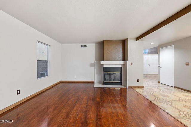 unfurnished living room with hardwood / wood-style flooring and a large fireplace