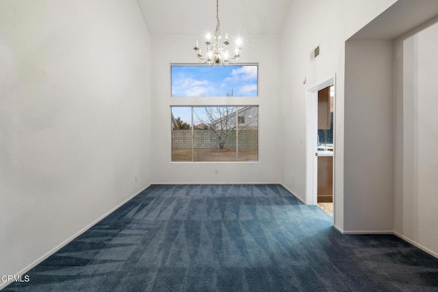 carpeted spare room featuring a notable chandelier and a towering ceiling