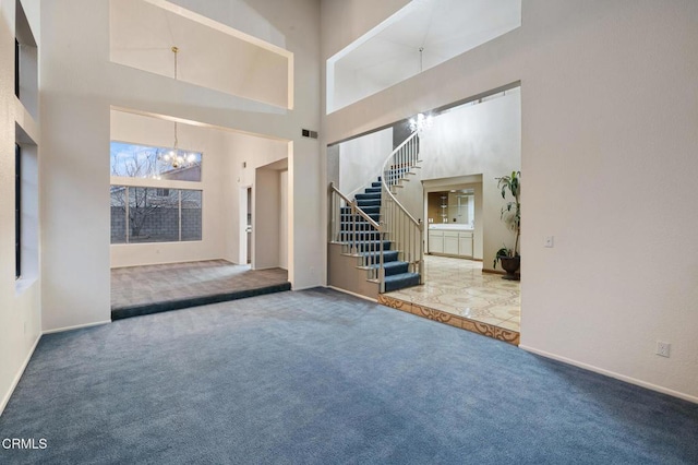 unfurnished living room with a notable chandelier, a towering ceiling, and carpet