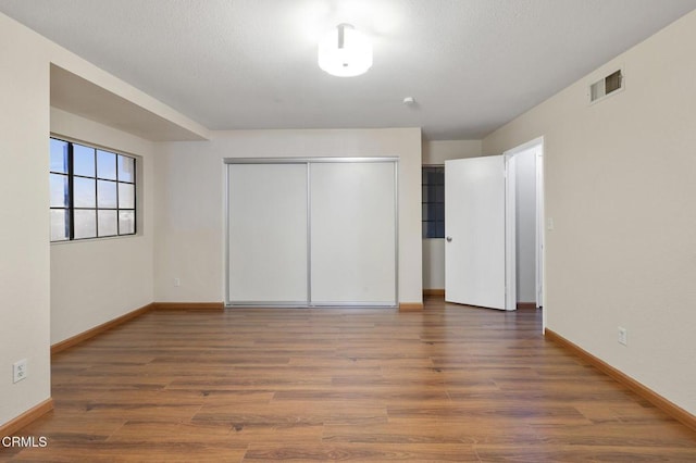 unfurnished bedroom featuring dark wood-type flooring and a closet