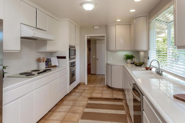 kitchen featuring sink, white cabinetry, tasteful backsplash, tile countertops, and appliances with stainless steel finishes