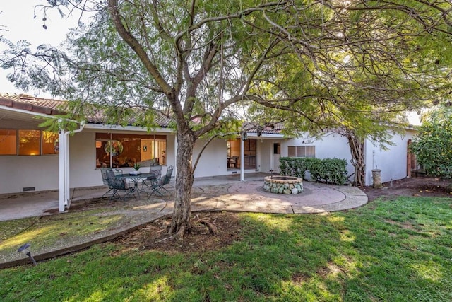 back of house with a yard, a patio area, and an outdoor fire pit