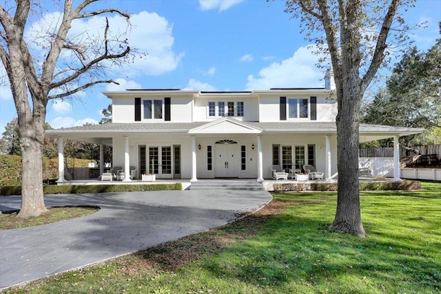 view of front of home featuring french doors, covered porch, and a front yard