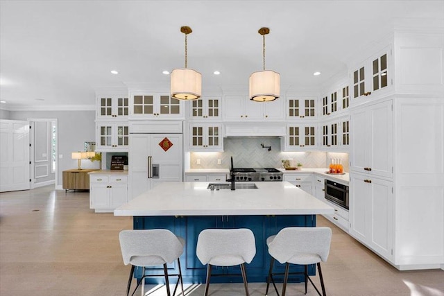 kitchen featuring sink, white cabinetry, built in appliances, hanging light fixtures, and a kitchen island with sink