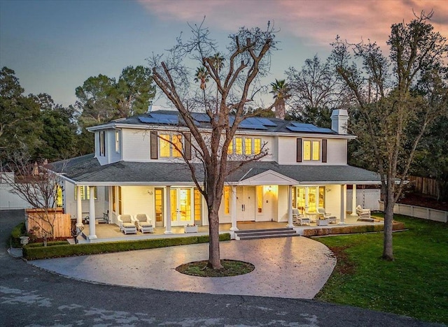 back house at dusk with a yard, an outdoor hangout area, a patio, and solar panels