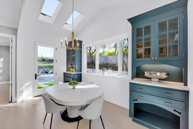 dining room featuring vaulted ceiling with skylight and an inviting chandelier