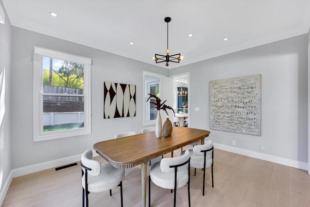 dining space with crown molding, a chandelier, and light hardwood / wood-style flooring