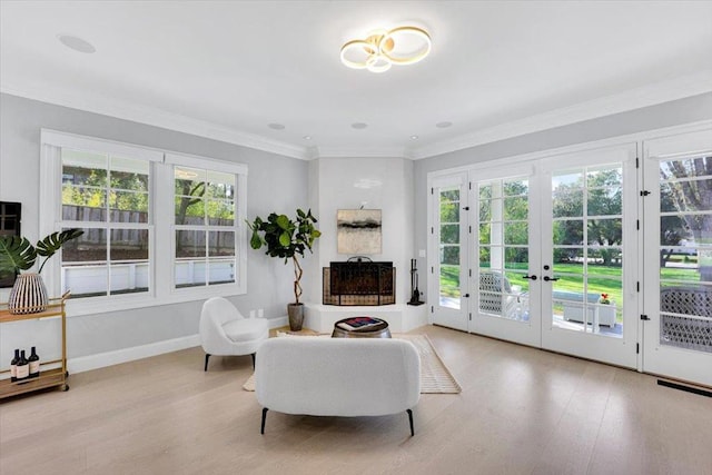 sitting room with french doors, ornamental molding, and light hardwood / wood-style flooring