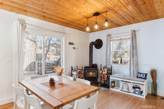 dining space featuring a wood stove, wood ceiling, and light hardwood / wood-style floors