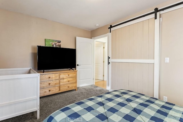 bedroom featuring a barn door and dark carpet