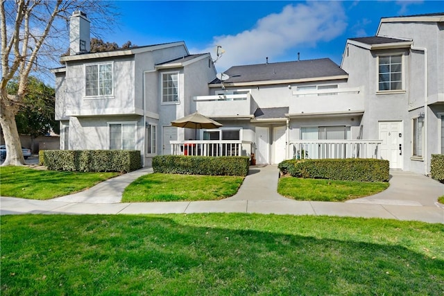 rear view of property with a lawn and a balcony