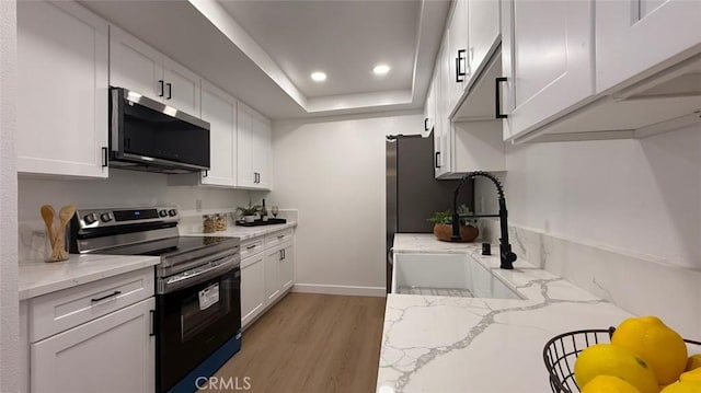 kitchen with light stone countertops, appliances with stainless steel finishes, sink, and white cabinets