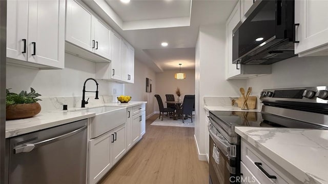 kitchen featuring white cabinetry, appliances with stainless steel finishes, light stone countertops, and light hardwood / wood-style flooring