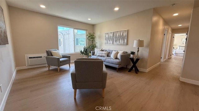 living room featuring a wall mounted air conditioner and light hardwood / wood-style floors