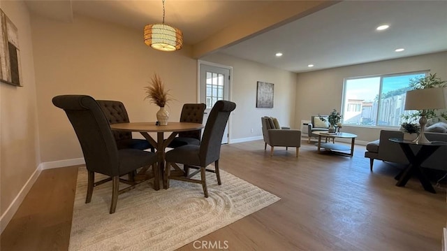 dining area featuring beamed ceiling and light wood-type flooring