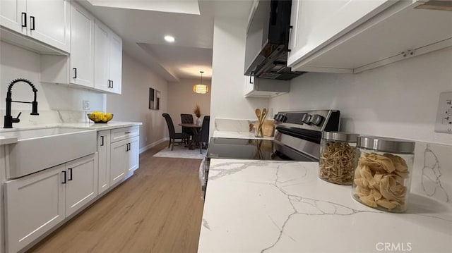 kitchen featuring electric stove, sink, white cabinetry, light stone countertops, and light wood-type flooring