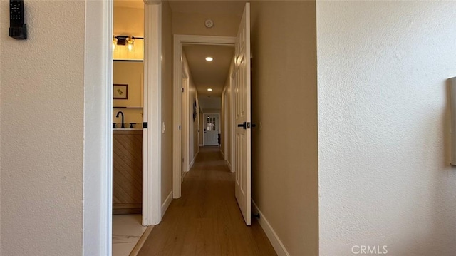 corridor with sink and light hardwood / wood-style floors