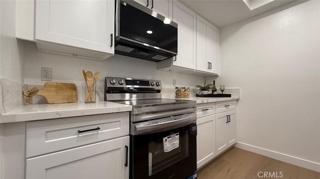 kitchen with wood-type flooring, white cabinets, light stone counters, and stainless steel electric range