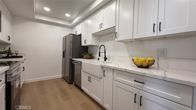 kitchen with sink, light hardwood / wood-style flooring, white cabinets, and appliances with stainless steel finishes