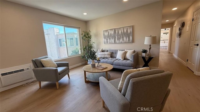 living room featuring an AC wall unit and light hardwood / wood-style floors