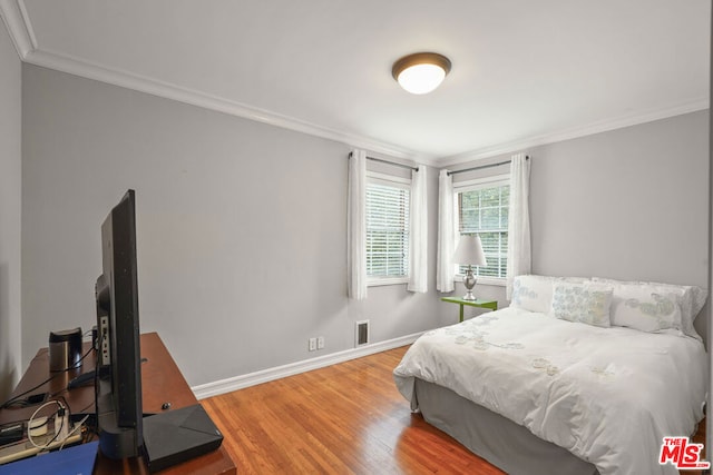 bedroom with wood-type flooring and crown molding