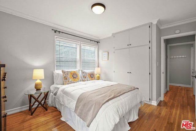 bedroom featuring hardwood / wood-style flooring, crown molding, and a closet