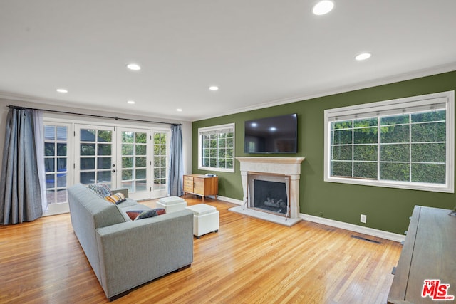 living room with light hardwood / wood-style flooring, ornamental molding, and french doors