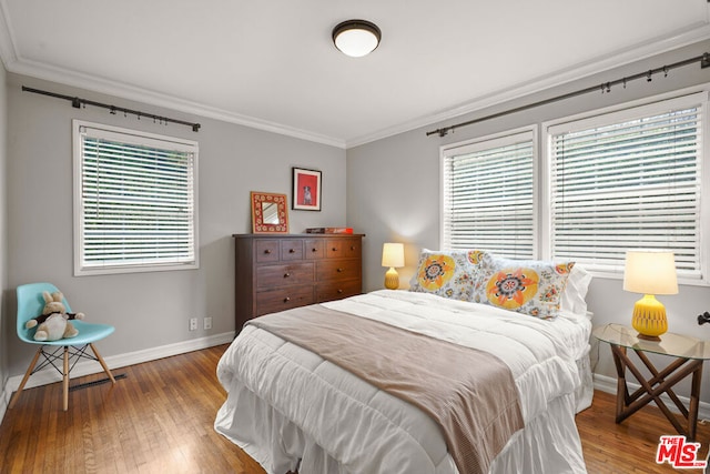 bedroom with ornamental molding, wood-type flooring, and multiple windows