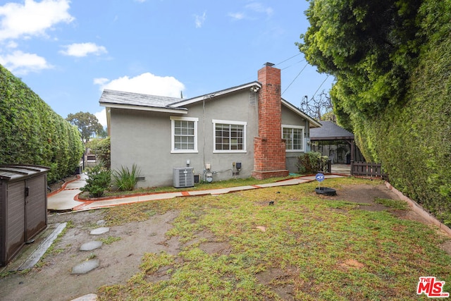 back of house with a gazebo and central AC