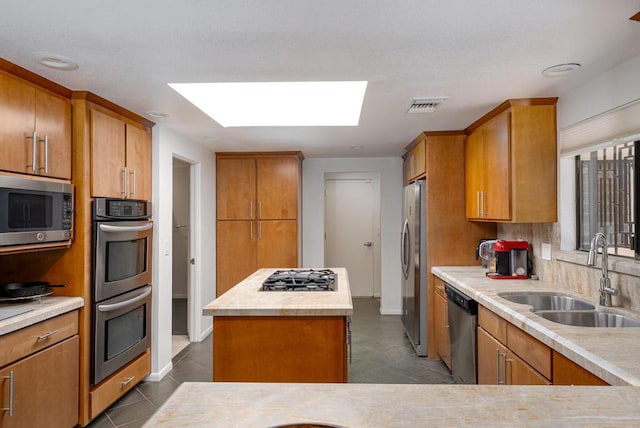 kitchen featuring sink, a center island, appliances with stainless steel finishes, tile patterned flooring, and decorative backsplash