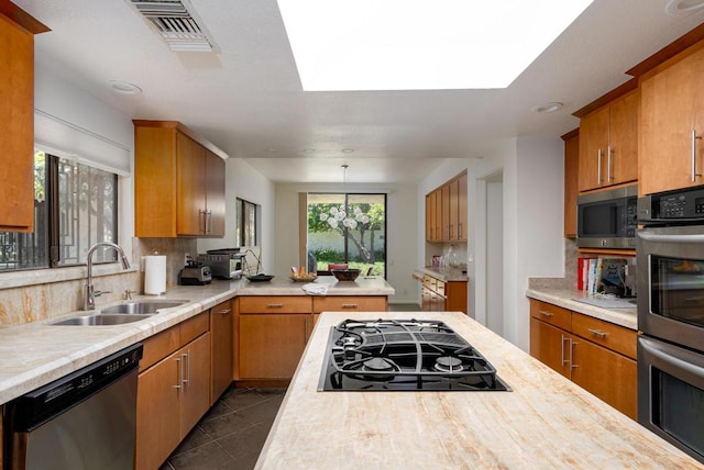 kitchen with pendant lighting, sink, backsplash, dark tile patterned floors, and stainless steel appliances