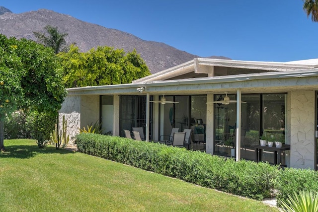 back of property with a mountain view, a lawn, and a sunroom