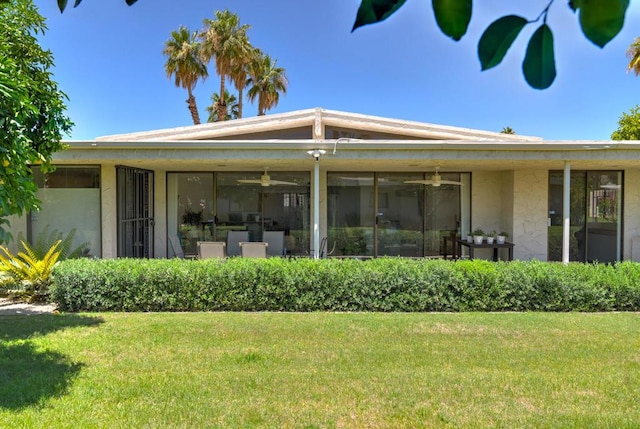 back of property featuring ceiling fan and a lawn