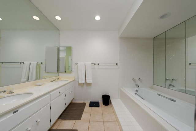 bathroom featuring a relaxing tiled tub, vanity, and tile patterned floors