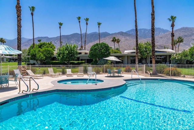 view of swimming pool featuring a hot tub, a mountain view, and a patio area